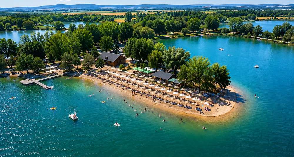 Pogled iz vazduha na belocrkvansko jezero sa peščanom plažom, ležaljkama i okolnim zelenilom